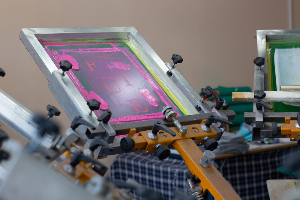 Carousel Frame, squeegee and plastisol color paint Serigraphy silk screen print process at clothes factory